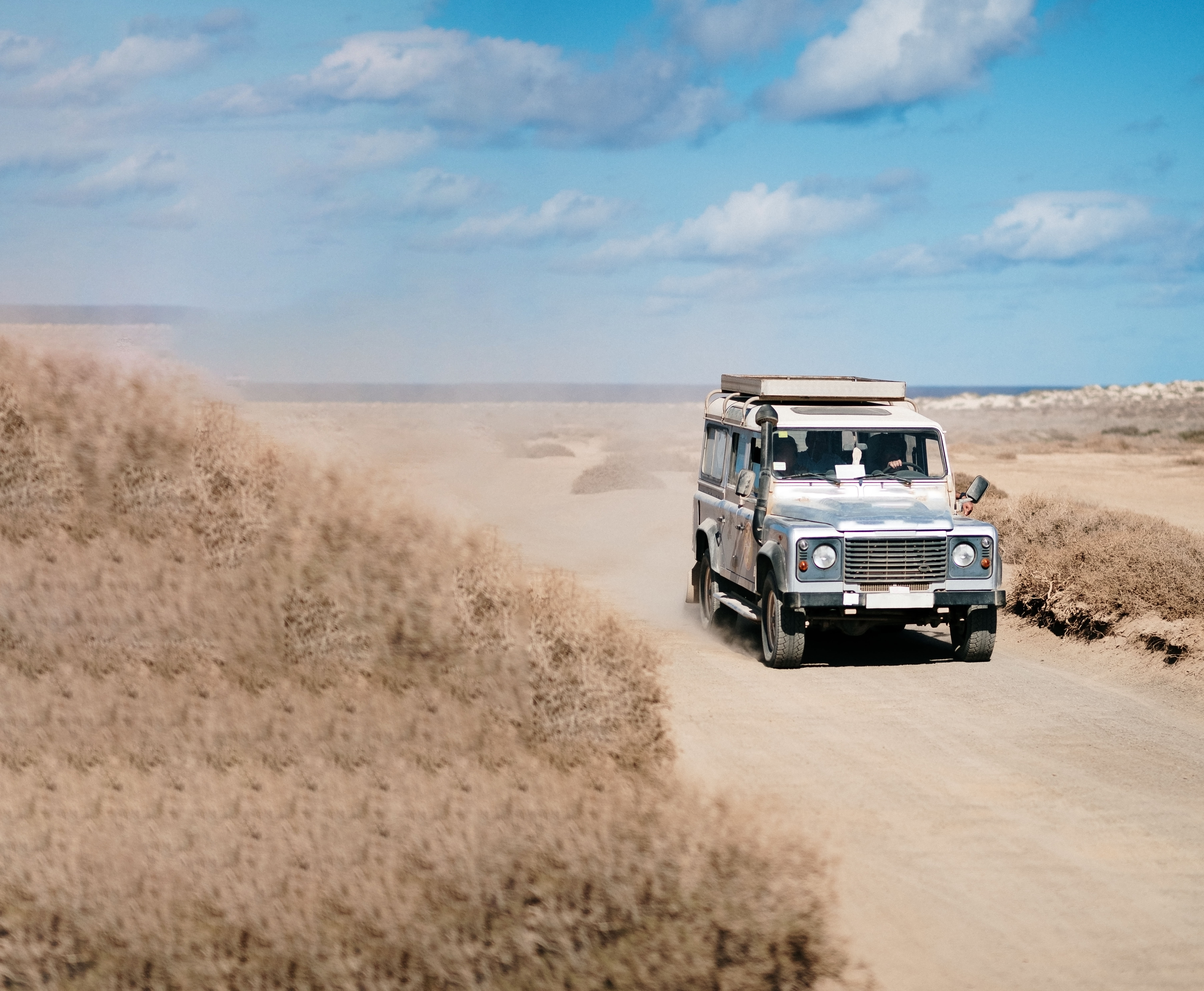 A vertical shot of an off-road car moving in a desert road